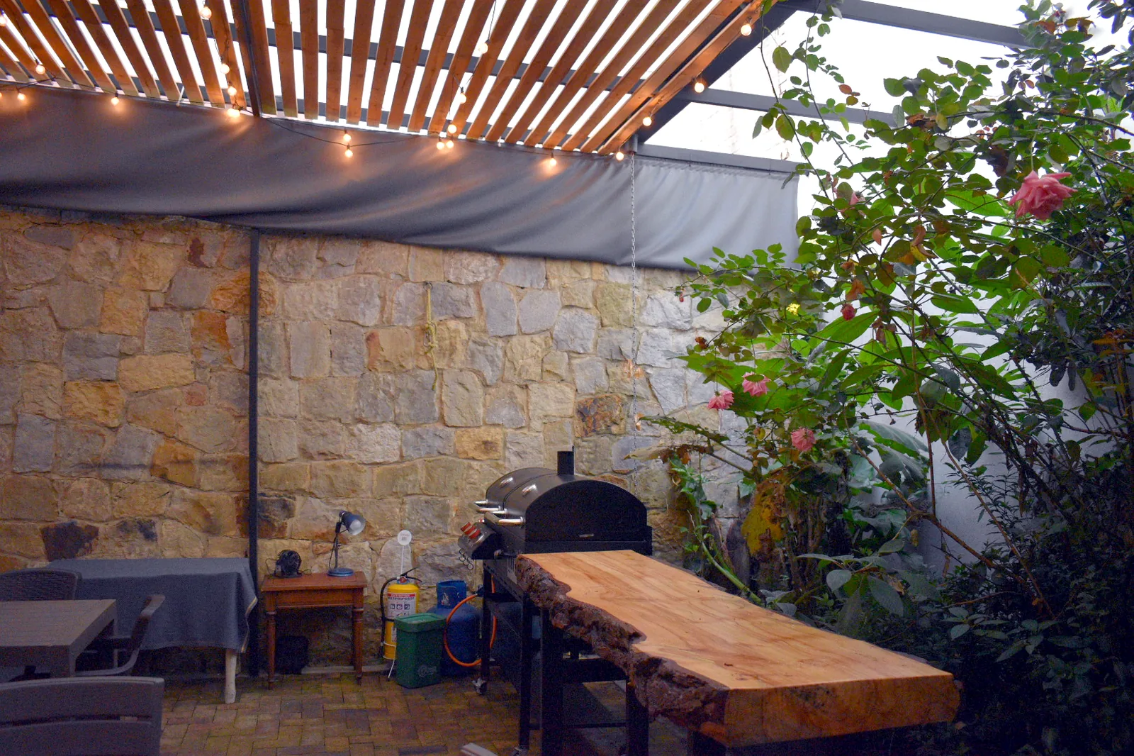 Terraza de Casa Apolonia con muro en piedra, pérgola y luces colgantes